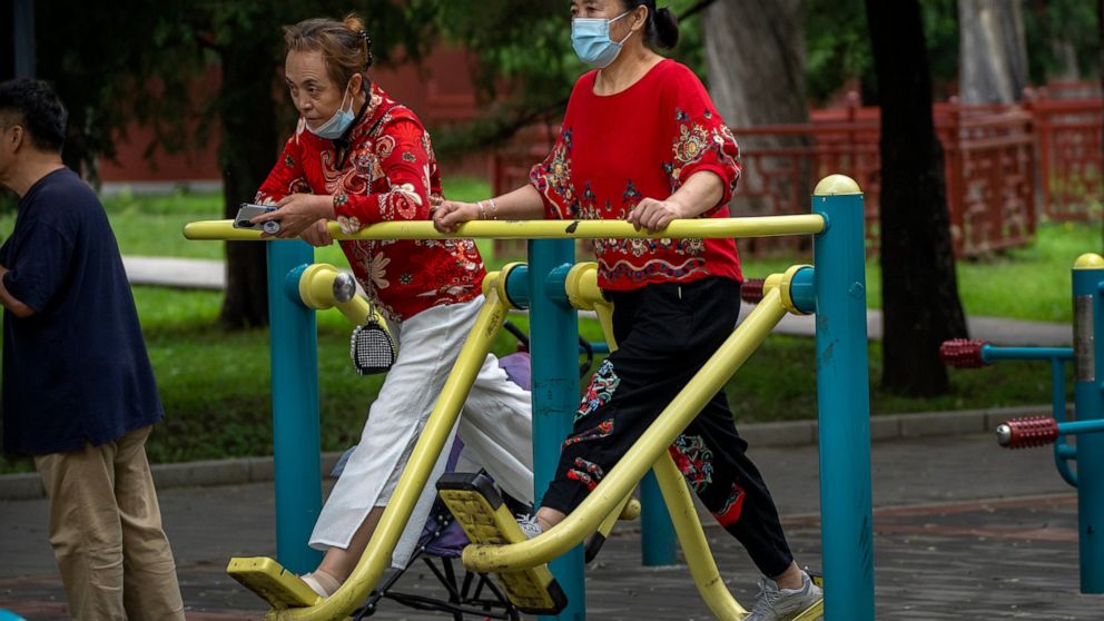 A woman wearing a face mask to protect against COVID-19 uses an exercise machine at a public park in Beijing, Thursday, Sept. 9, 2021. (AP Photo/Mark Schiefelbein)
