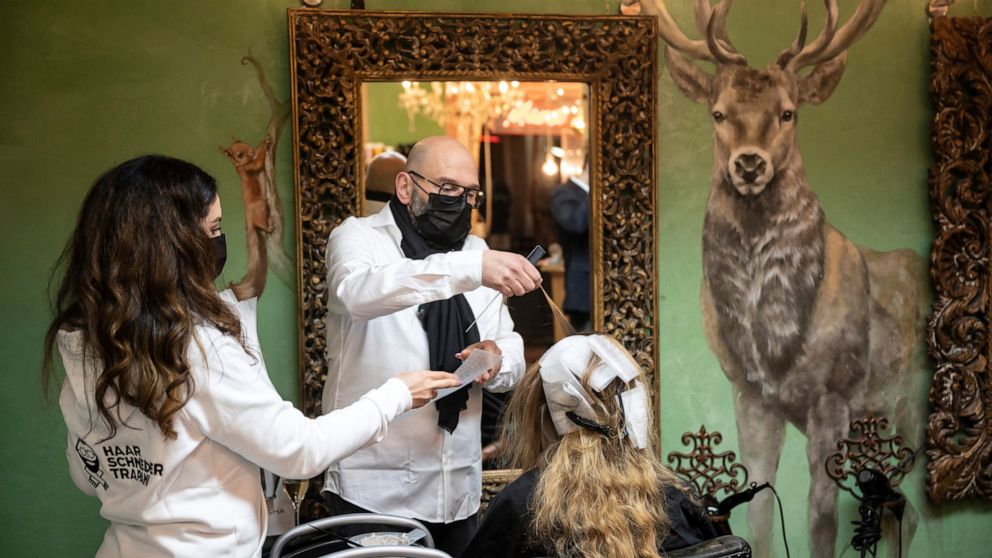 Marco Trapani is standing next to one of his first customers shortly after midnight in Dortmund, Germany early morning March 1, 2021. After about a two-and-a-half-month of closing to battle the coronavirus pandemic, the first hairdressers return to w