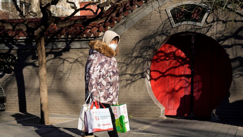 A resident wearing mask past by a traditional entrance way in Beijing, Friday, Dec. 16, 2022. A week after China dramatically eased some of the world's strictest COVID-19 containment measures, uncertainty remained Thursday over the direction of the p