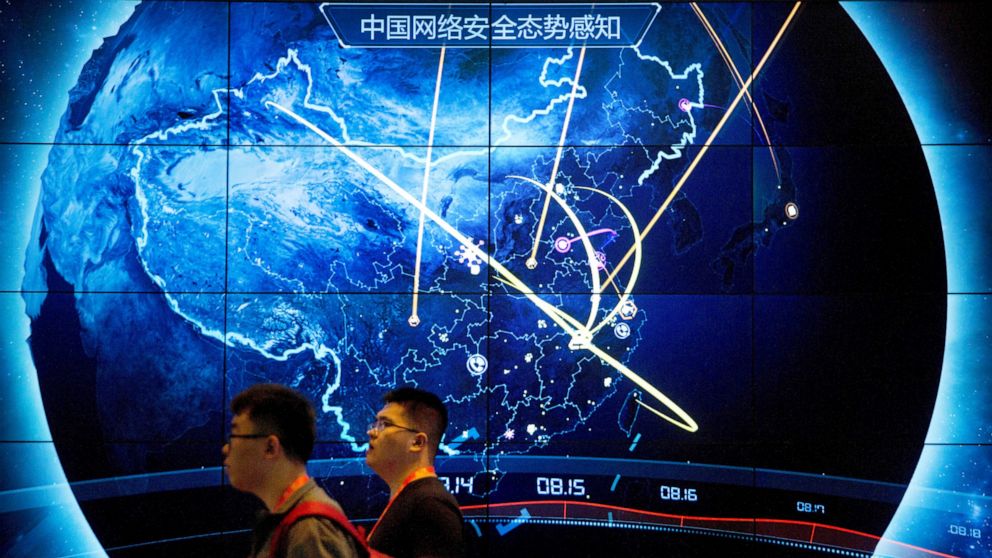FILE - In this Sept. 12, 2017, file photo, attendees walk past an electronic display showing recent cyberattacks in China at the China Internet Security Conference in Beijing. Cybersecurity and space are emerging risks to the global economy, adding t
