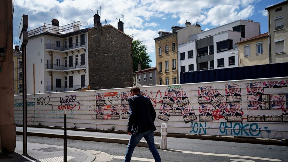 A man passes by electoral posters reading "Melenchon Prime Minister" in Lyon, central France, Tuesday, June 7, 2022. The legislative elections will take place on June 12 and 19, 2022. (AP Photo/Laurent Cipriani)