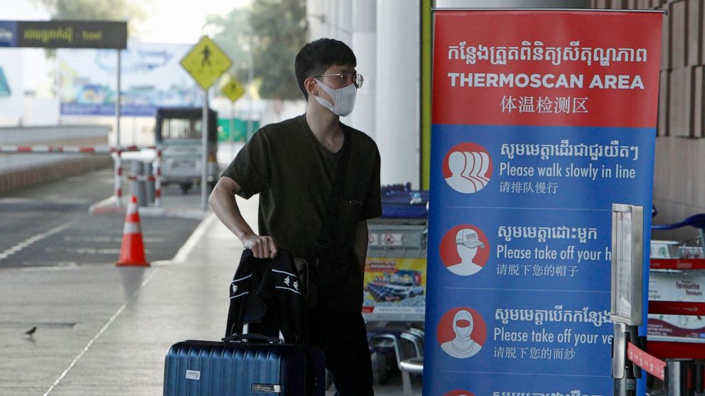 FILE - A tourist wearing a face mask enters an area of thermo scan at the quiet Phnom Penh International Airport in Phnom Penh, Cambodia, April 3, 2020. Cambodia on Thursday, April 21, 2022, reduced the quarantine period from two weeks to one for arr