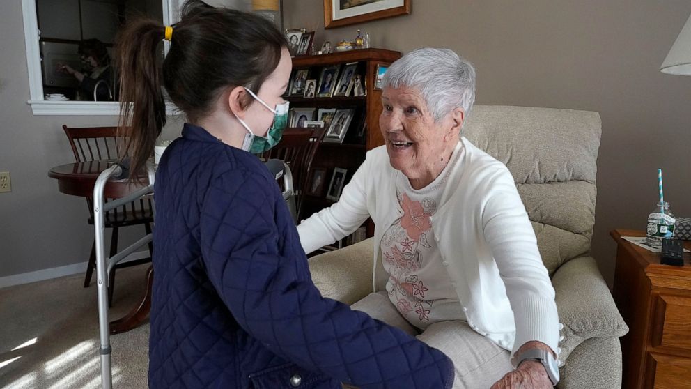 Eileen Quinn, 98, right, a resident at New Pond Village retirement community, in Walpole, Mass., greets her great-granddaughter Maeve Whitcomb, 6, of Norwood, Mass., left, Sunday, March 21, 2021, at the retirement community, in Walpole. Quinn said it