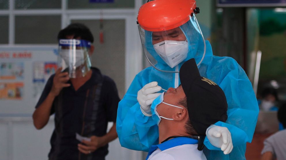 A medical worker takes swab sample from a man in Vung Tau city, Vietnam Saturday, Aug. 21, 2021. Vietnam's government said it is sending troops to Ho Chi Minh city to help deliver food and aid to households as it further tightens restrictions on peop