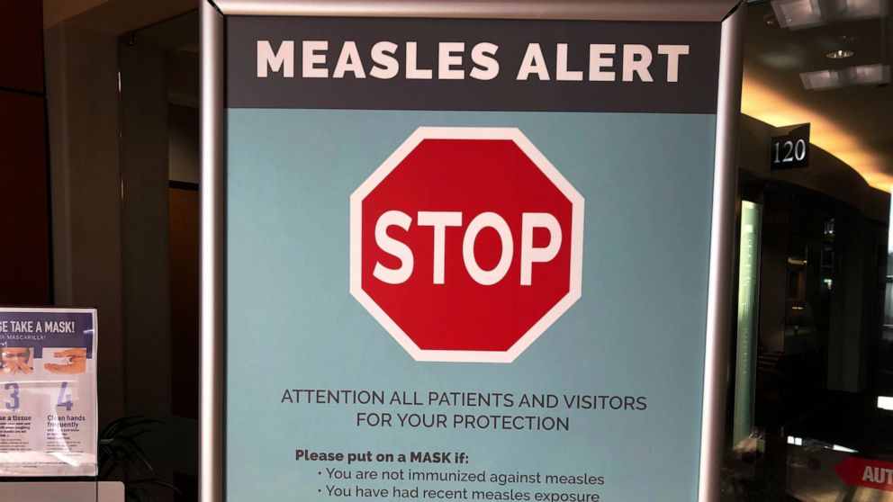 FILE - In this Jan. 30, 2019 file photo signs posted at The Vancouver Clinic in Vancouver, Wash., warn patients and visitors of a measles outbreak. Washington state lawmakers voted Tuesday, April 23, 2019, to remove parents' ability to claim a person