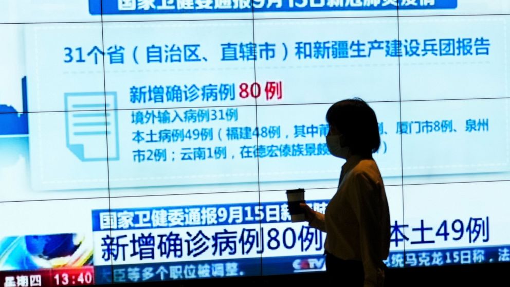 A woman wearing a face mask to help curb the spread of the coronavirus is silhouetted as she walks by a TV screen showing CCTV reporting number of COVID-19 cases in China, at a shopping mall in Beijing, Thursday, Sept. 16, 2021. (AP Photo/Andy Wong)