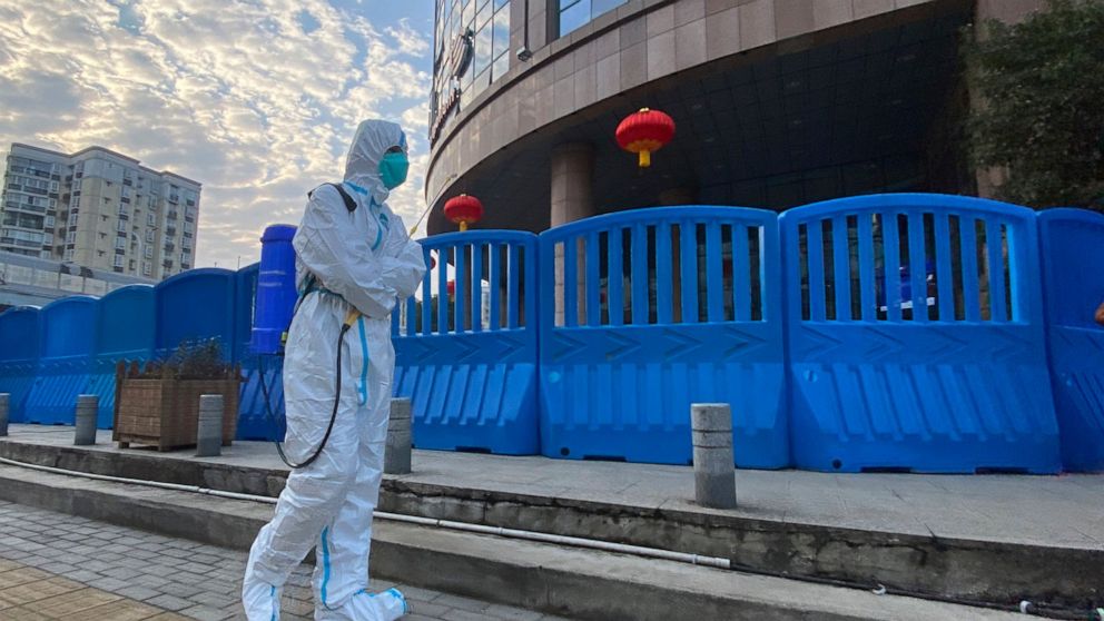 FILE - A worker in protectively overalls and carrying disinfecting equipment walks outside the Wuhan Central Hospital, China on Feb. 6, 2021. Experts drafted by the World Health Organization to help investigate the origins of the coronavirus pandemic