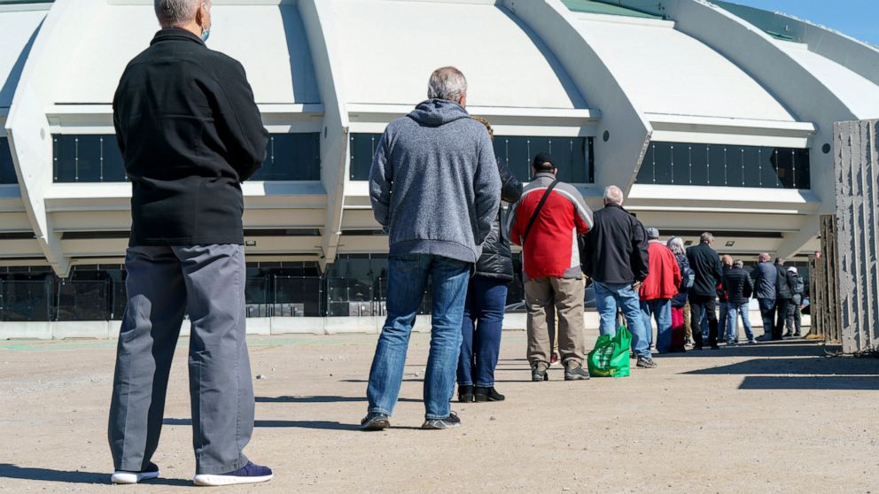 People wait in line at a COVID-19 vaccination clinic to receive the AstraZeneca vaccine at Olympic Stadium in Montreal, on Thursday, April 8, 2021. Quebecers 55 and over can now get the AstraZeneca vaccine at walk-in clinics across the province. (Pau