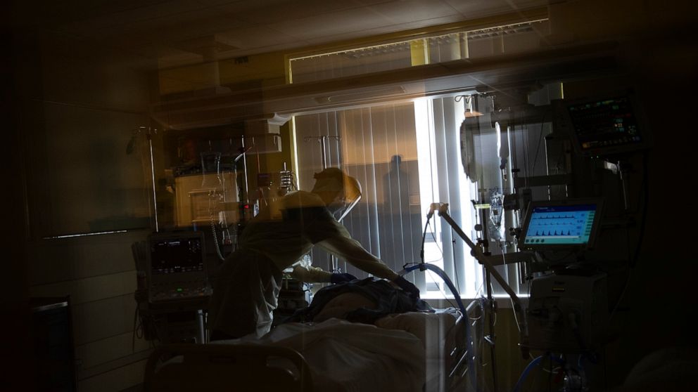 In this photograph taken from behind a window a medical staffer works in the intensive care ward for Covid-19 patients at the Jessa Ziekenhuis hospital during a partial lockdown to prevent the spread of coronavirus in Hasselt, Belgium, Friday, April 