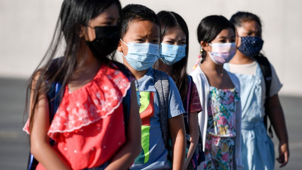 Masked students wait to be taken to their classrooms at Enrique S. Camarena Elementary School, Wednesday, July 21, 2021, in Chula Vista, Calif. The school is among the first in the state to start the 2021-22 school year with full-day, in-person learn