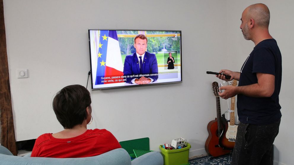 The family Ithurrioz watches French President Emmanuel Macron during his televised address, in Bayonne, southwestern France, Sunday, June 14, 2020. French President Emmanuel Macron is giving an address to his nation after an unusually long silence, a