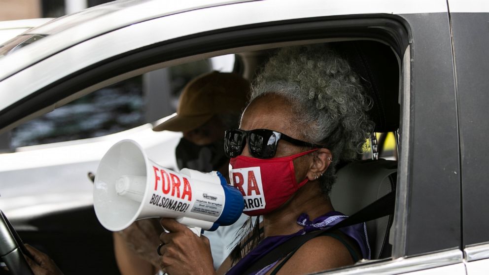 A demonstrator uses a bullhorn to shout slogans in a caravan to protest against the government's response in combating COVID-19 and demanding the impeachment of Brazil's President Jair Bolsonaro, in Rio de Janeiro, Brazil, Saturday, Jan. 23, 2021. (A