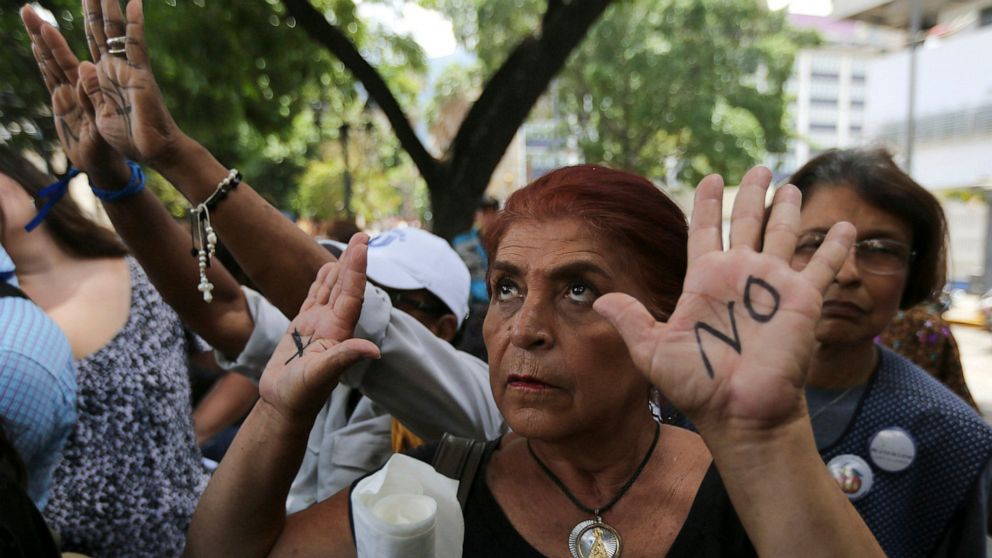 Demonstrators hold up their hands painted with the Spanish phrase: "No more deaths" outside the J. M. de los Ríos pediatric hospital after the reported deaths of four children there this month in Caracas, Venezuela, Monday, May 27, 2019. The deaths o