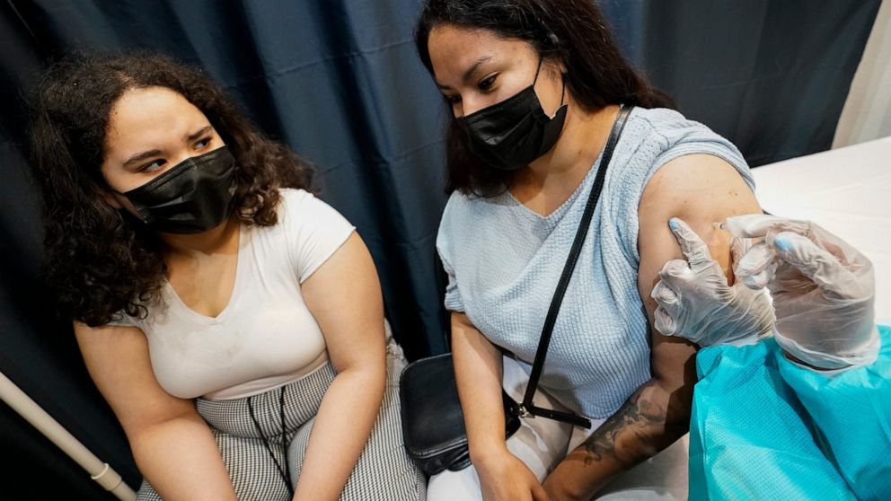 FILE - A health care worker inoculates Evelyn Pereira, right, of Brooklyn, with the first dose of the Pfizer COVID-19 vaccine as her daughter Soile Reyes, 12, looks on, Thursday, July 22, 2021, at the American Museum of Natural History in New York. T