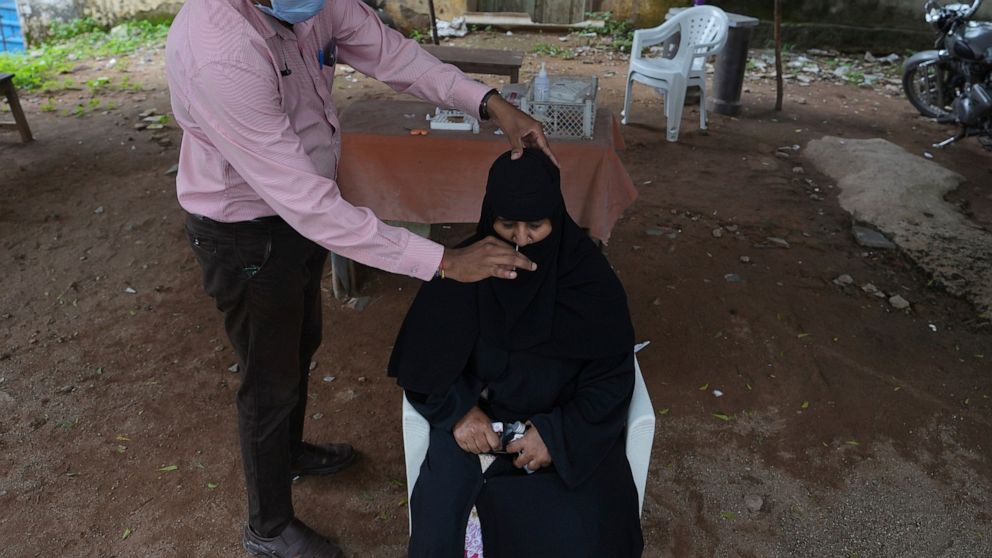 FILE - A women gets her nasal swab sample taken to be tested for COVID-19 at Government Fever Hospital in Hyderabad, India, Saturday, Aug. 20, 2022. India has begun randomly testing international passengers arriving at its airports for COVID-19, the 