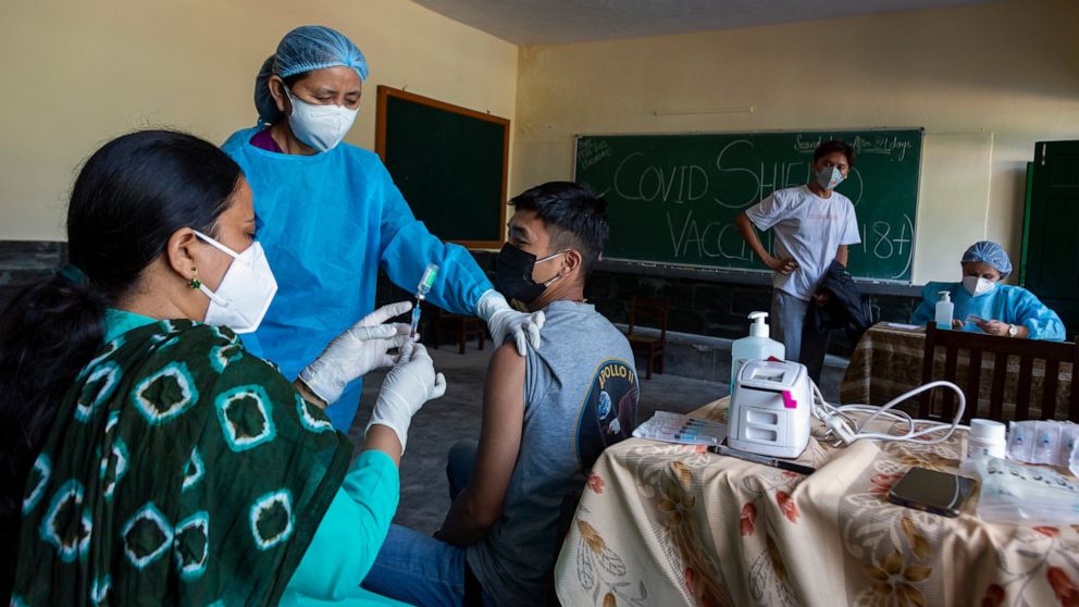 An exile Tibetan nurse in protective suit prepares another Tibetan to receive a Covishield -19 vaccine in Dharmsala, India, Saturday, June 19, 2021. (AP Photo/Ashwini Bhatia)