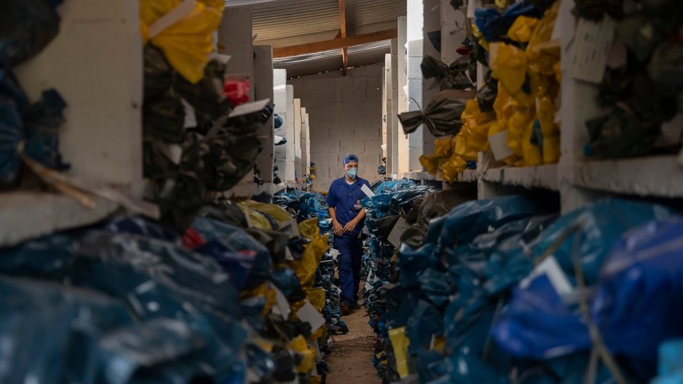 A cemetery worker stands inside an ossuary at the Vila Formosa cemetery, which does not charge for their gravesites or storage, in Sao Paulo, Brazil, Friday, June 12, 2020. Three years after burials, remains are routinely exhumated and stored in plas