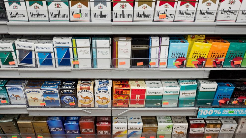FILE - This Aug. 28, 2017 file photo shows cigarettes displayed on a store shelf in New York. With a new law enacted in December 2019, anyone under 21 can no longer legally buy cigarettes, cigars or any other tobacco products in the U.S. It also appl