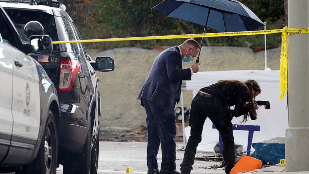 FILE - A Los Angeles Police investigator takes pictures in the rain, as investigators gather evidence in the death of an adult male found dead at a homeless encampment in downtown Los Angeles on March 12, 2021. A new report shows that nearly 2,000 ho