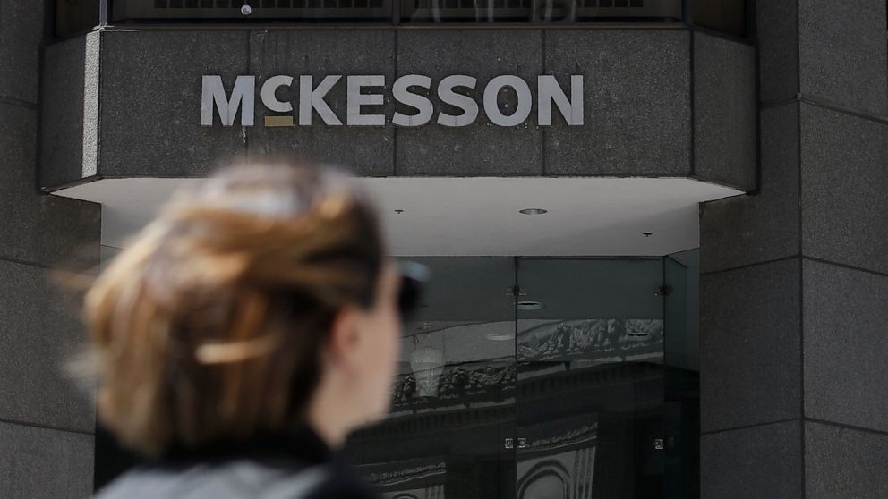 FILE - In this July 17, 2019 file photo, a pedestrian passes a McKesson sign on an office building in San Francisco. Four companies say they'll move ahead with a $26 billion settlement of lawsuits over the opioid crisis. An announcement from drug dis
