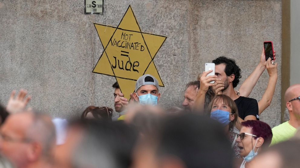 FILE - In this Saturday, July 24, 2021 file photo, people stage a protest against the "green pass" in Milan, Italy. Protesters in Italy and in France have been wearing yellow Stars of David, like the ones Nazis required Jews to wear to identify thems