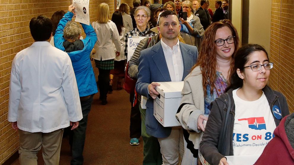 FILE - In this Oct. 24, 2019 file photo, supporters of Yes on 802 Oklahomans Decide Healthcare, calling for Medicaid expansion to be put on the ballot, carry boxes of petitions into the office of the Oklahoma Secretary of State, in Oklahoma City. Ten