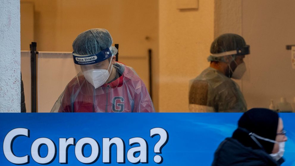 FILE --A woman walks past a Covid-19 test center in Frankfurt, Germany, Monday, Jan. 24, 2022. Four German regions plan to scrap rules requiring people infected with the coronavirus to isolate at home, arguing that the pandemic has evolved and it’s t