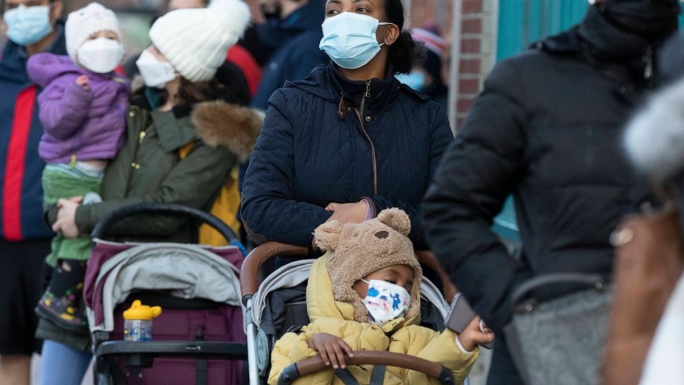 Makda Yesuf, center, and her son Jaden wait in line at a COVID-19 walk-in testing site, Sunday, Dec. 5, 2021, in Cambridge, Mass. (AP Photo/Michael Dwyer)