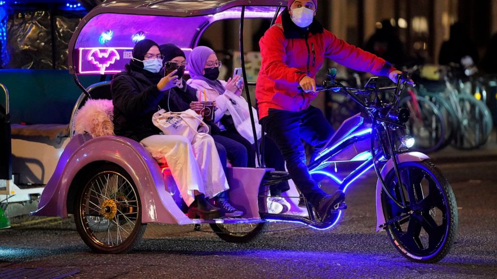 People ride in a bike taxi near Leicester Square in London, Thursday, Dec. 30, 2021. British Prime Minister Boris Johnson has resisted implementing new restrictions on business and social interactions during the holiday season, instead emphasizing an