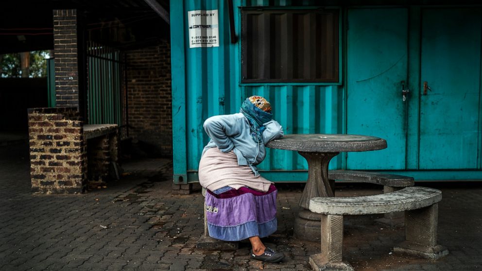 A woman living near the traditional medicine market waits to receive food baskets from private donors, Monday, April 13, 2020 downtown Johannesburg. Because of South Africa's imposed lockdown to contain the spread of COVID-19, many are not able to wo