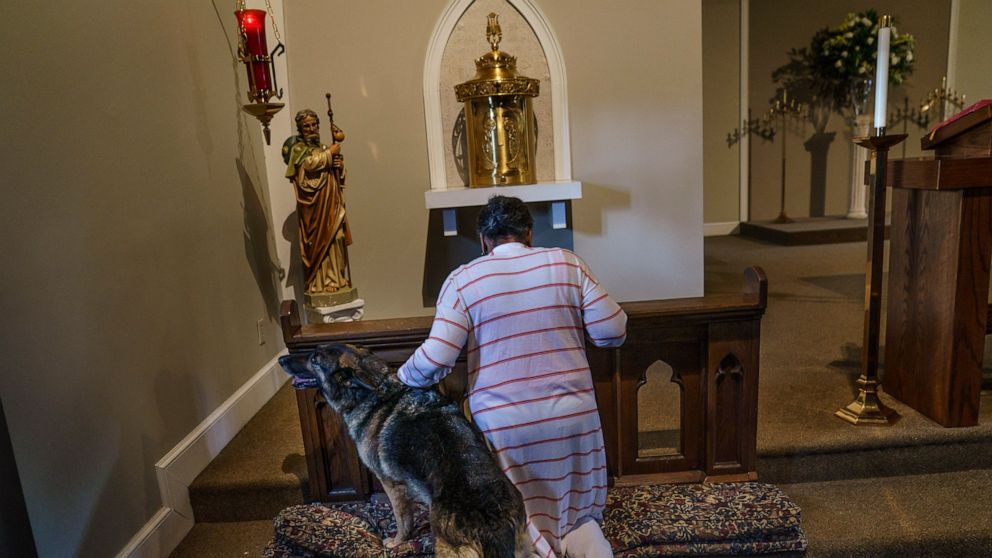 Tanya Britton prays with her dog, Sybil, by her side, while helping to prepare for Mass at St. James Catholic Church in Tupelo, Miss., Tuesday, May 24, 2022. Many people across the U.S. are reacting with horror to the Supreme Court's abortion decisio