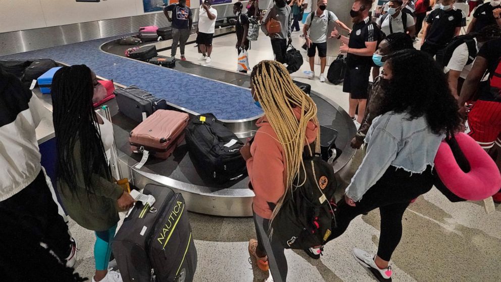 FILE - In this May 28, 2021 file photo, travelers wait for their luggage at a baggage carousel at Miami International Airport in Miami. The airline industry’s recovery from the pandemic passed a milestone as more than 2 million people streamed throug