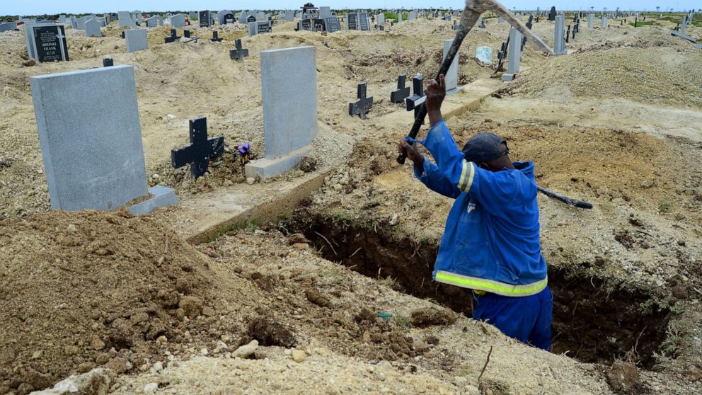 A grave digger prepares graves at the Motherwell Cemetery in Port Elizabeth, South Africa, Friday, Dec. 4, 2020. Health Minister Zweli Mkhize announced on Wednesday, Dec. 9, 2020 that the country is now experiencing a Covid-19 pandemic second wave. (