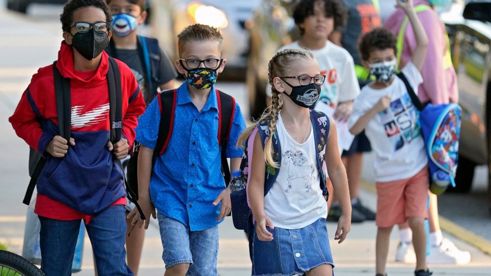 FILE - In this Tuesday, Aug. 10, 2021, file photo, students, some wearing protective masks, arrive for the first day of school at Sessums Elementary School in Riverview, Fla. The on-again, off-again ban imposed by Republican Gov. Ron DeSantis to prev