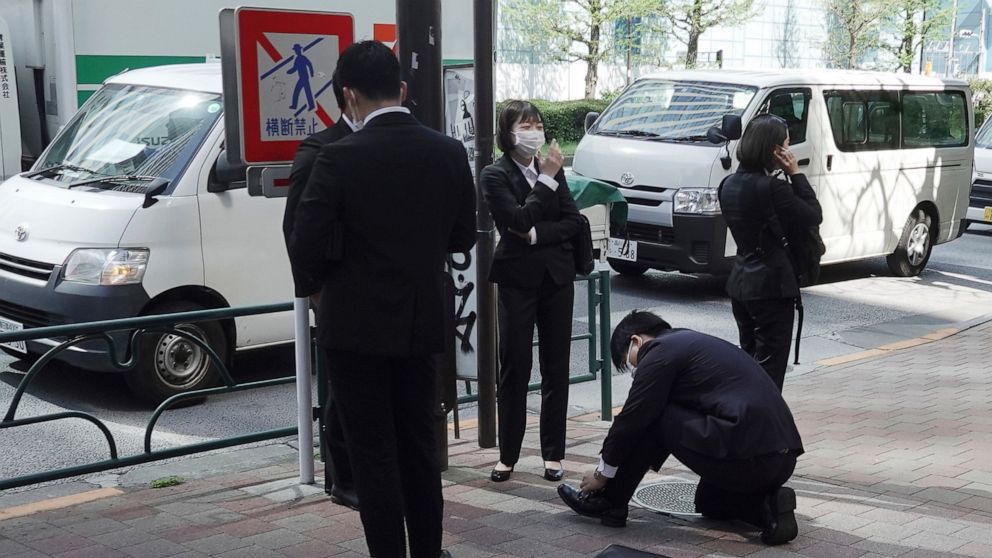 Employees wearing protective masks to help curb the spread of the coronavirus stand on a sidewalk Wednesday, April 7, 2021, in Tokyo. (AP Photo/Eugene Hoshiko)