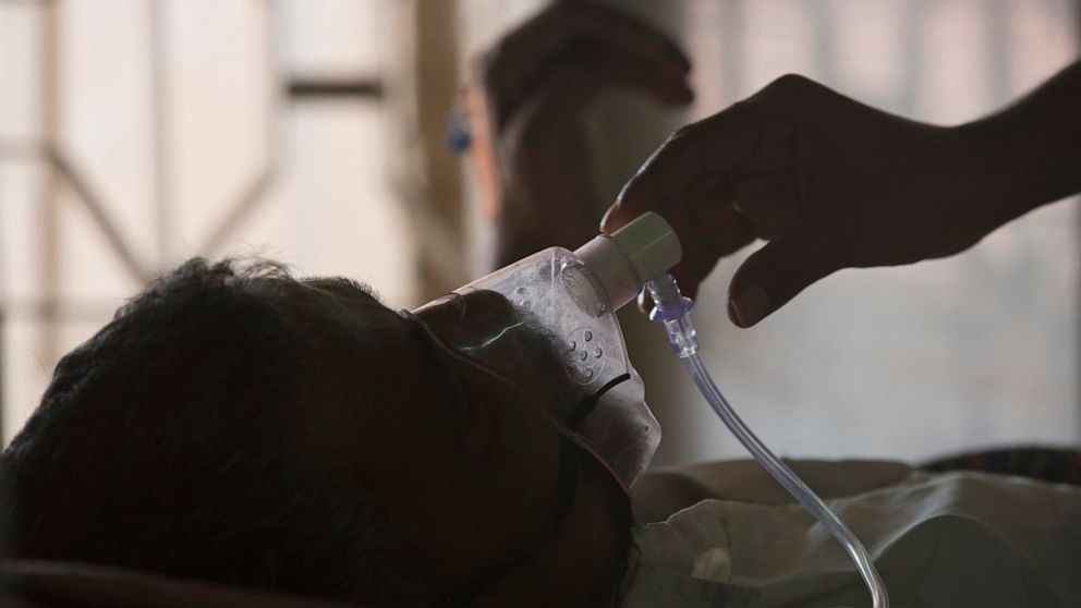 FILE - A relative adjusts the oxygen mask of a tuberculosis patient at a TB hospital on World Tuberculosis Day in Hyderabad, India, March 24, 2018. The number of people infected with tuberculosis, including the kind resistant to drugs, rose globally 