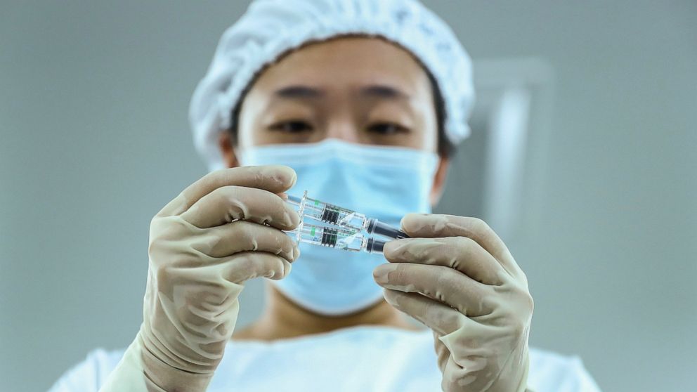 In this photo Dec. 25, 2020 released by Xinhua News Agency, a staff member inspects syringes of COVID-19 inactivated vaccine products at a packaging plant of the Beijing Biological Products Institute Co., Ltd, a unit of state-owned Sinopharm in Beiji