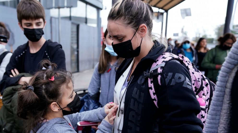 A woman from Ukraine stands with her children before crossing into the United States, Thursday, March 10, 2022, in Tijuana, Mexico. U.S. authorities allowed the woman and her three children to seek asylum Thursday, a reversal from a day earlier when 