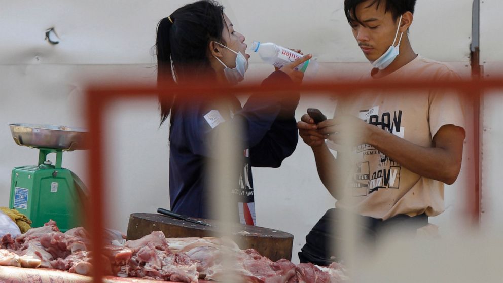 A couple of local vendors waits for customers as they sell pork meats at a motor-cart's mobile market in Phnom Penh, Cambodia, Sunday, April 25, 2021. The country's capital Phnom Penh has been locked down for two weeks from April 15, following a shar