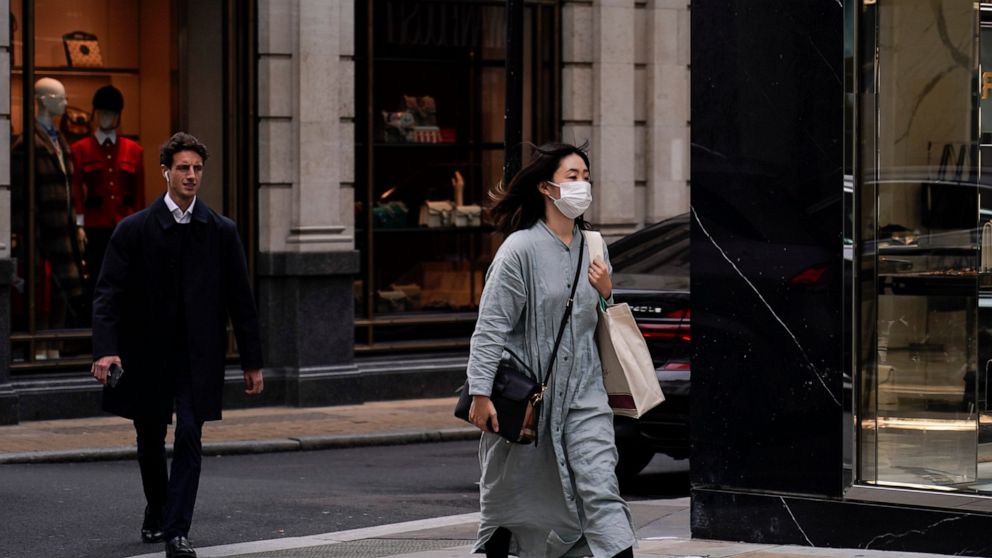 A woman wears a face mask as she walks in London, Tuesday, Oct. 19, 2021. Many scientists are pressing the British government to re-impose social restrictions and speed up booster vaccinations as coronavirus infection rates, already Europe's highest,