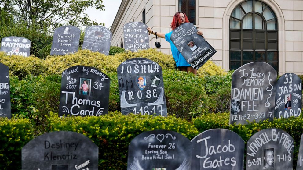 FILE - Jayde Newton helps to set up cardboard gravestones with the names of victims of opioid abuse outside the courthouse where the Purdue Pharma bankruptcy is taking place in White Plains, N.Y., on Aug. 9, 2021. A federal appeals panel is scheduled