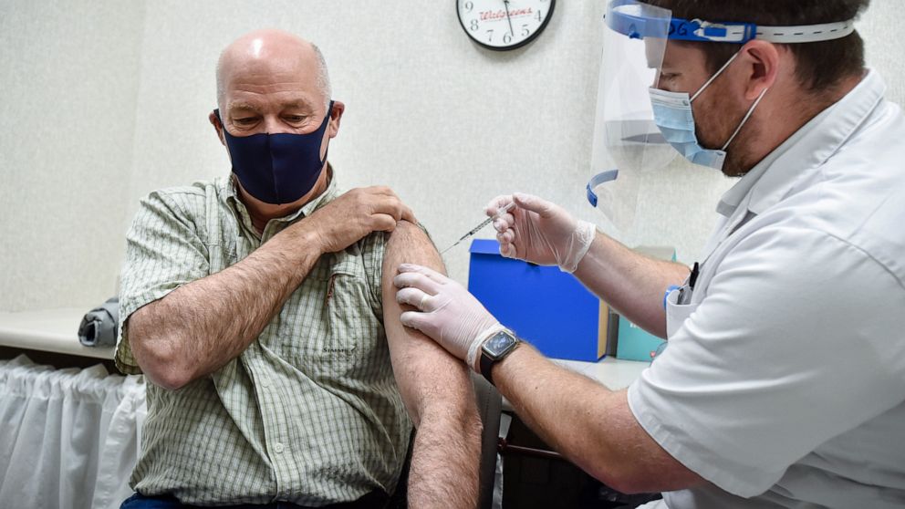 FILE - In this April 1, 2021 file photo, Montana Gov. Greg Gianforte receives a shot of the Pfizer COVID-19 vaccine from pharmacist Drew Garton at a Walgreen's pharmacy in Helena, Mont. While large companies across the U.S. have announced that the CO