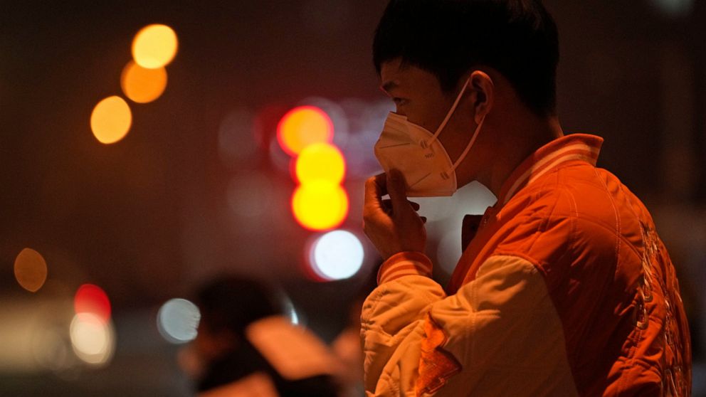 A man adjusts his mask on the street of Beijing, Sunday, Nov. 20, 2022. China on Sunday announced its first new death from COVID-19 in nearly half a year as strict new measures are imposed in Beijing and across the country to ward against new outbrea