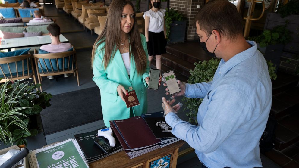 FILE - In this Tuesday, June 22, 2021 file photo, a restaurant employee, right, checks a visitor's COVID-19 vaccination QR code at the entrance of a restaurant in Moscow, Russia. Faced with worrying surges of coronavirus infections driven by the more