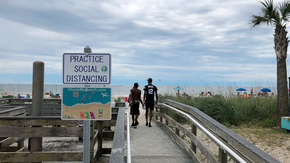 A sign in Myrtle Beach, S.C., Thursday, June 18, 2020, asks people to maintain social distancing on the beach. People are flocking to South Carolina's beaches for vacation after being cooped up by COVID-19 for months. But the virus is taking no vacat
