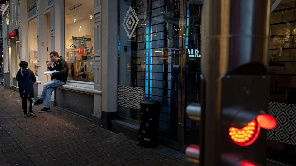 FILE- Closed restaurants because of a lockdown forced people to eat outdoors next to a closed shop in Amsterdam, Netherlands, Thursday, Dec. 30, 2021, as the fast-spreading coronavirus variant omicron rages through Western Europe. The new Dutch gover