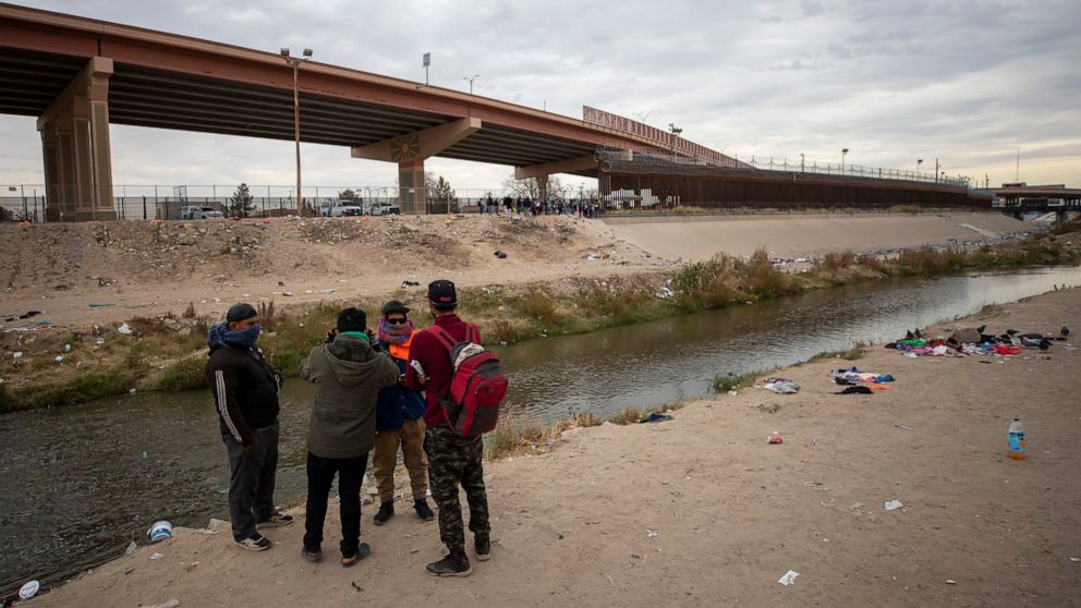 A small group of migrants discuss whether or not to cross the Rio Grande from Ciudad Juarez, Mexico and surrender to the Border Patrol in El Paso, Texas, Sunday, Dec. 18, 2022. Texas border cities were preparing Sunday for a surge of as many as 5,000
