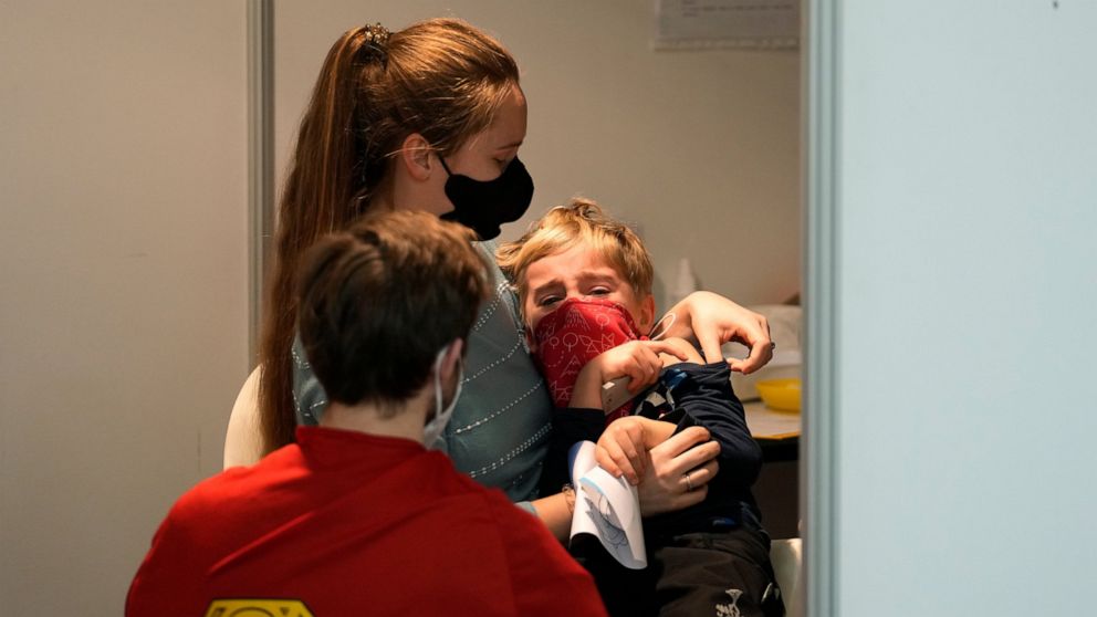 FILE- Volunteer dressed in a costume talks to a young boy who is about to receive the COVID-19 vaccine at vaccination center in Prague, Czech Republic, Saturday, Jan. 8, 2022. On Wednesday Jan. 19, 2022, the new Czech government dismissed the previou
