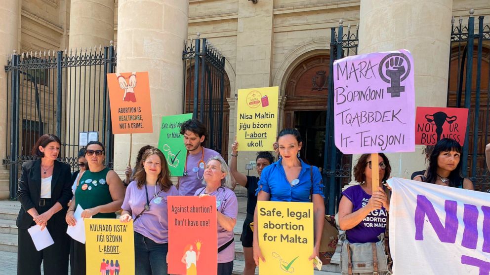Activists hold up banners in both English and Maltese reading, 'I decide', 'Abortion is a woman's right', and 'Abortion is healthcare, not a crime', as they stand outside the Maltese law courts in Valletta, Malta, Wednesday, June 15, 2022. A coalitio