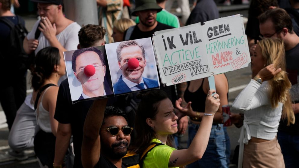 A person carries a placard depicting caretaker prime minister Mark Rutte and deputy prime minister Hugo de Jonge as clowns during a protest of organizers and fans of music festivals against the government's COVID-19 restrictions on large-scale outdoo